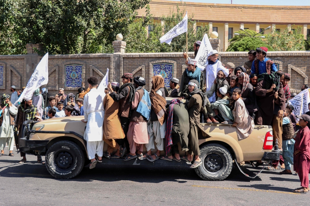 Afghans ride on a Taliban vehicle during the fifth anniversary celebrations of the Taliban's return to power, in Herat. — AFP