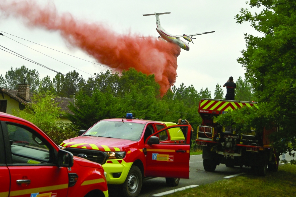 A French aircraft douses retarding liquid over trees during a wildfire in a forest near Luglon, south-western France. — Reuters