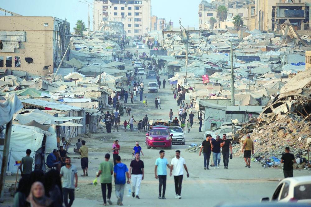 Displaced Palestinians walk past tents and destroyed buildings near the beachfront in Gaza City. — AFP