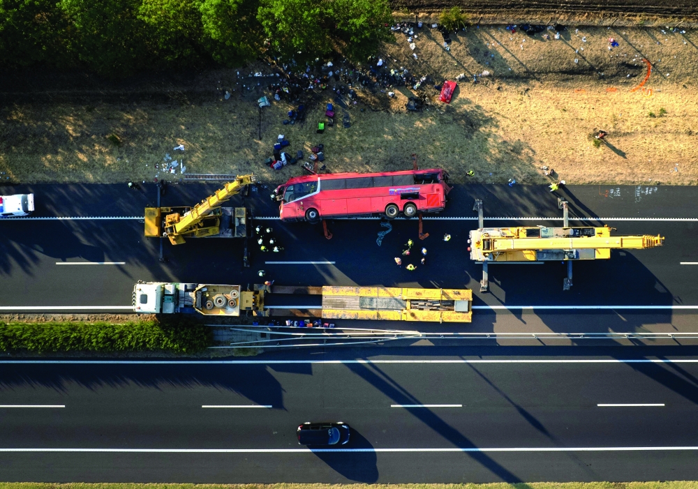 Rescuers and officials work at the wreckage of an overturned Polish tourist bus, about 150 km east of the Hungarian capital Budapest. — AFP