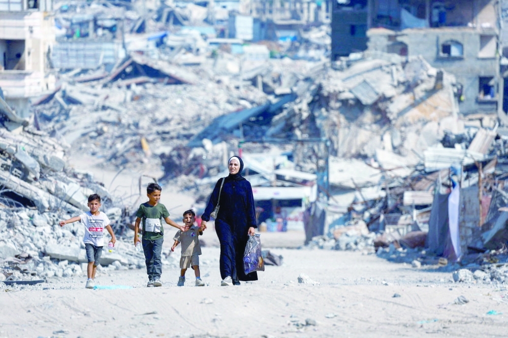 Palestinians walk past the rubble of residential buildings destroyed during the war, in Gaza City, August 15, 2026. REUTERS
