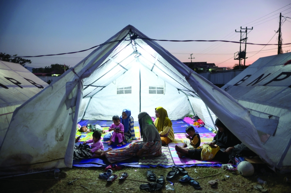 Women with children sit in a shelter at a makeshift evacuation centre at a stadium in Maumere, Indonesia. — Reuters