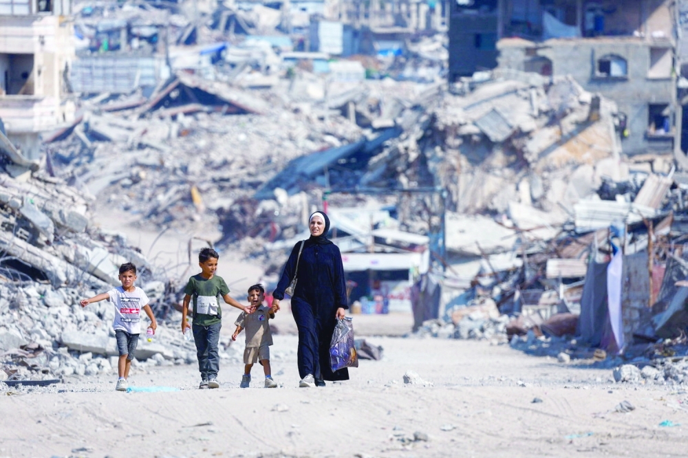 Palestinians walk past the rubble of residential buildings destroyed during the war in Gaza City on Sunday. — Reuters