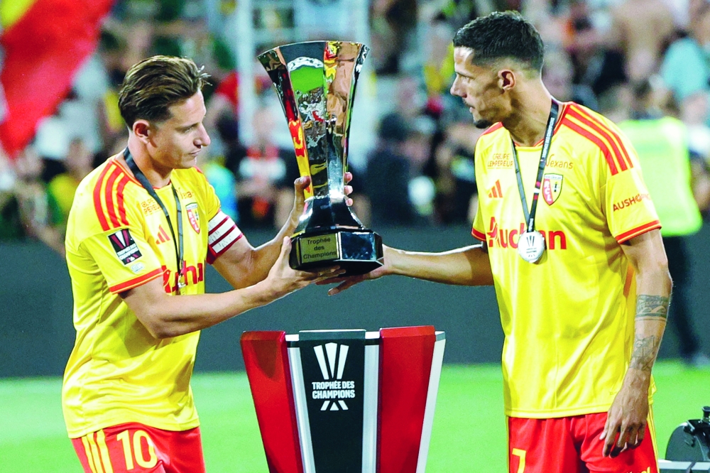 Lens' French forward #10 Florian Thauvin (L) and Lens' French forward #07 Florian Sotoca take the championship trophy to celebrate with teammates after winning the French Super Cup. — AFP