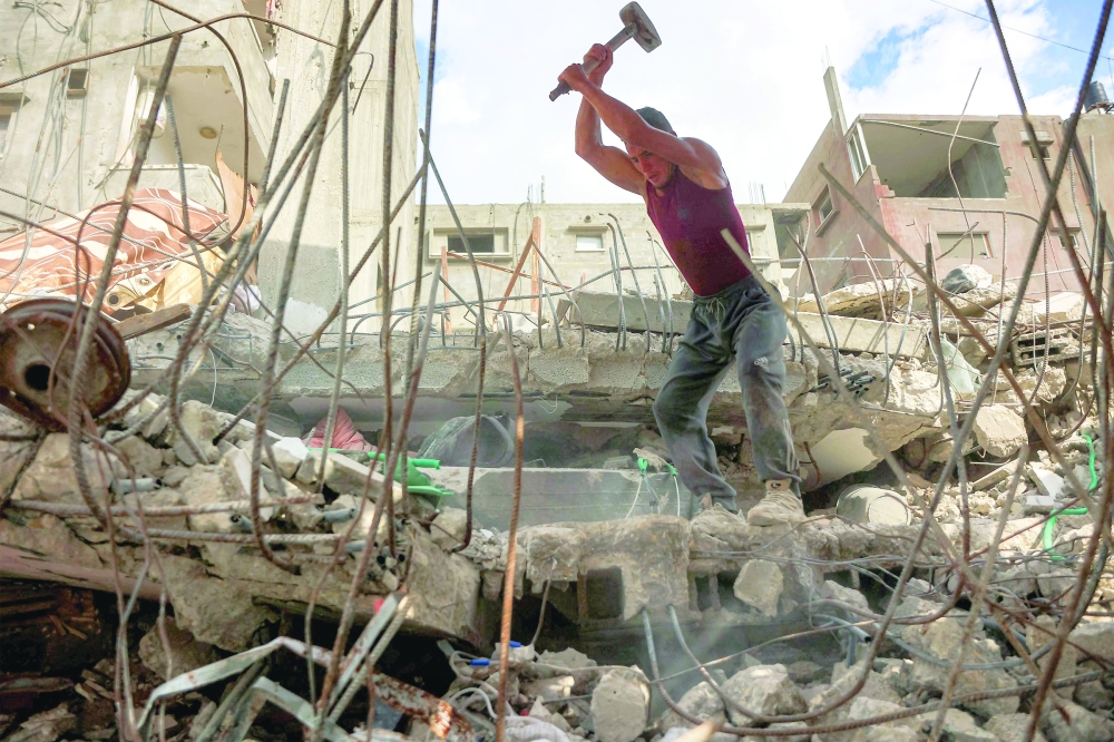 A salvage worker breaks the rubble of a building that was destroyed during Israeli strikes in Gaza. — AFP