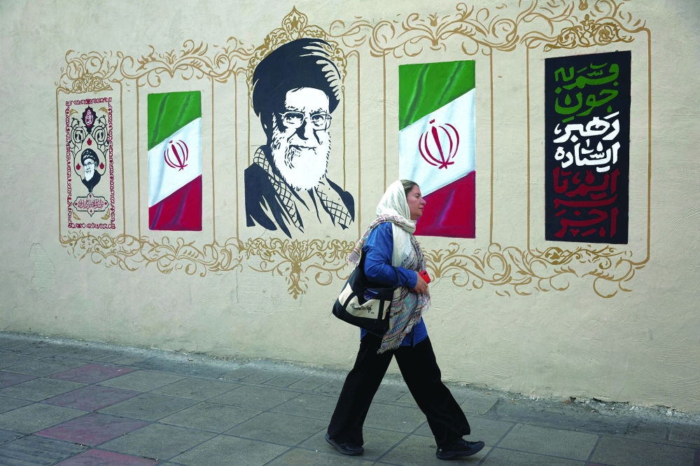 A woman walks by a mural depicting Iran's late Supreme Leader Ayatollah Ali Khamenei, on a street in Tehran, Iran. — Reuters