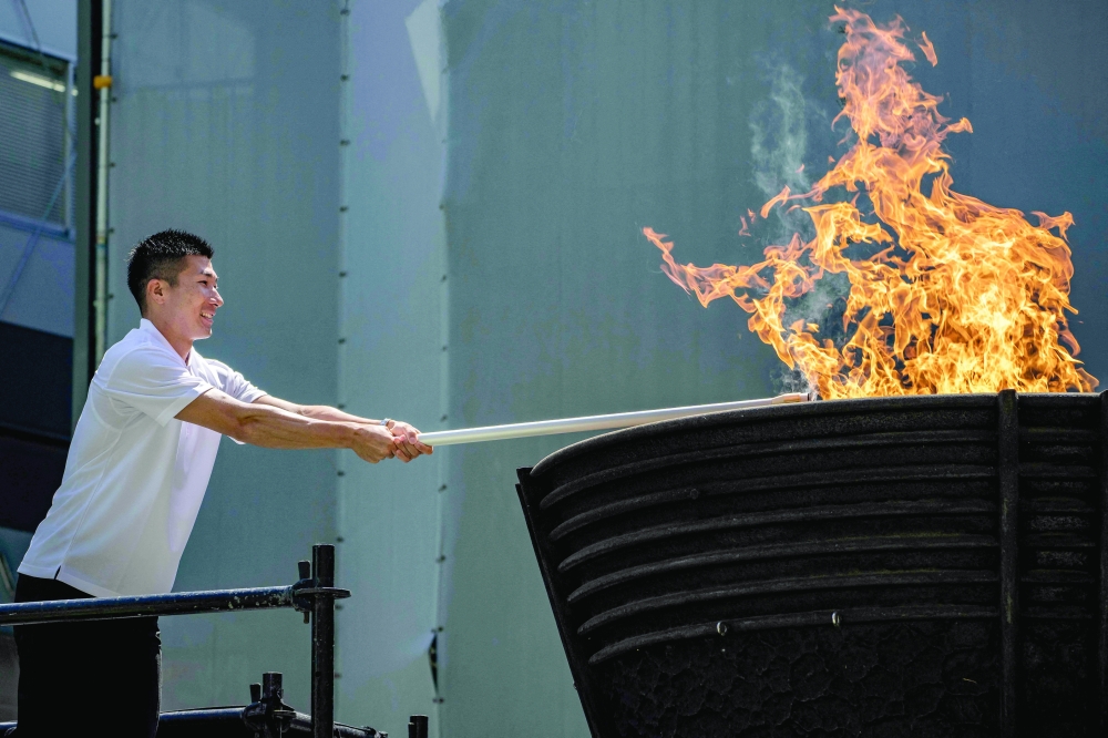 Japanese sprinter Yoshihide Kiryu lights the torch from the Olympic cauldron during the torch lighting ceremony for the 2026 Asian Games, outside the National Stadium in Tokyo on August 18. About 15,000 competitors and officials are expected at the event, which takes place in Nagoya and the wider Aichi area from September 19 to October 4. — AFP
