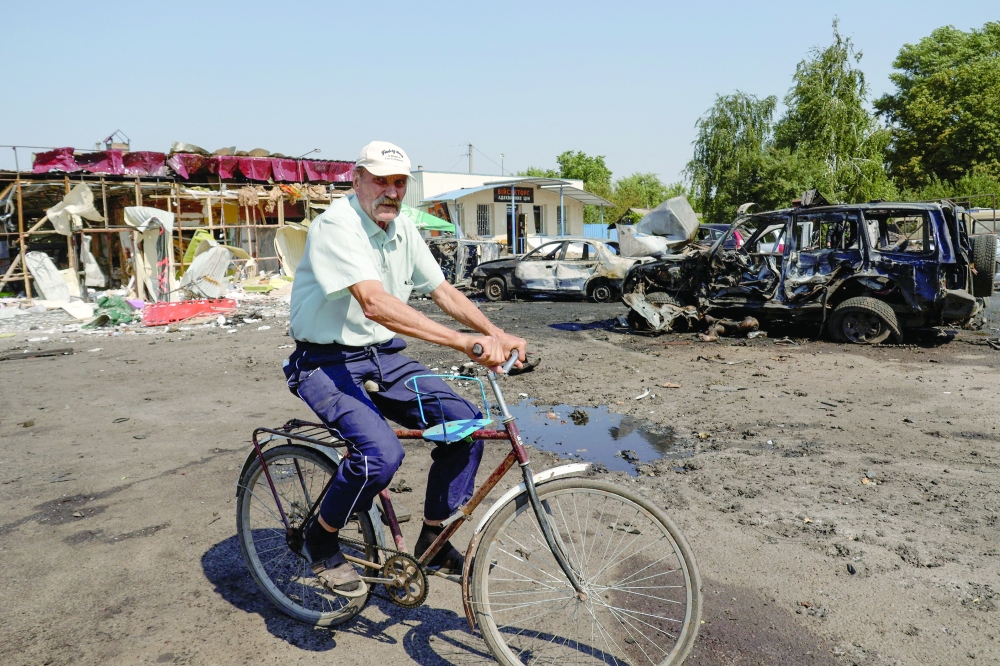 A resident rides a bicycle at the site of Russian drone strikes in the town of Pechenihy, Ukraine. — Reuters