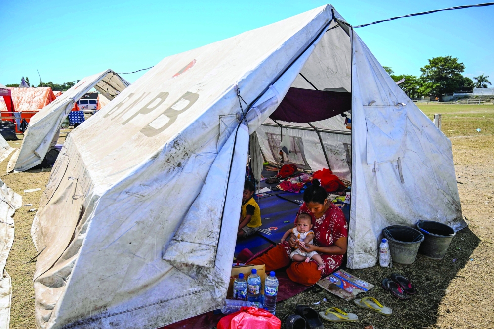 Villagers shelter in a tent in Maumere, East Nusa Tenggara, on August 18, 2026, following a 7.7-magnitude earthquake that struck Indonesia's Flores island on August 15.  Thousands of people displaced by a powerful earthquake in eastern Indonesia awaited much-needed aid on August 17 as they camped out at schools, police stations and government offices, with many stuck outside.
