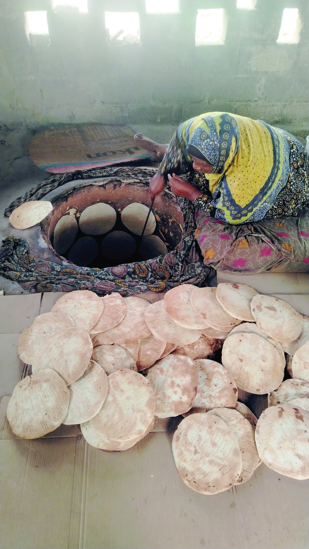 Taliiah bint Naseeb bin Farag, known as Umm Abdulrahman, prepares traditional Qalib bread in the Wilayat of Taqah.