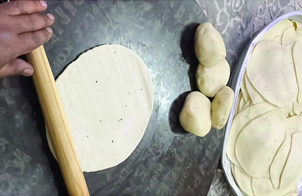 After resting, the dough is divided into small balls and flattened by hand.