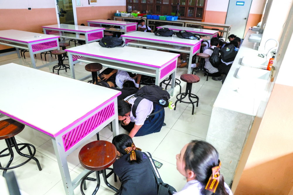 Students hide under tables during a drill by police officers to prepare for an active shooter scenario at Surasakmontree School in Bangkok. — Reuters