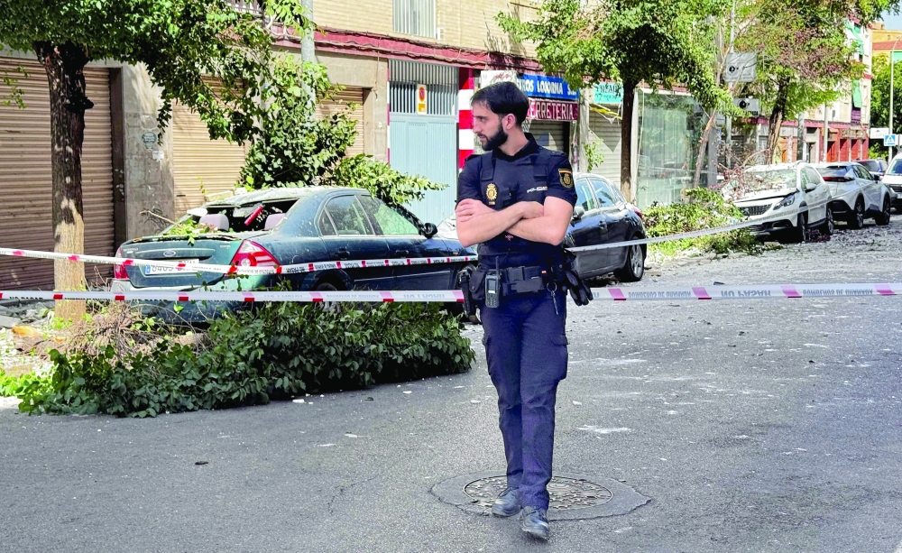 A policeman stands at a cordoned off street near damaged vehicles following an earthquake in Granada. — AFP