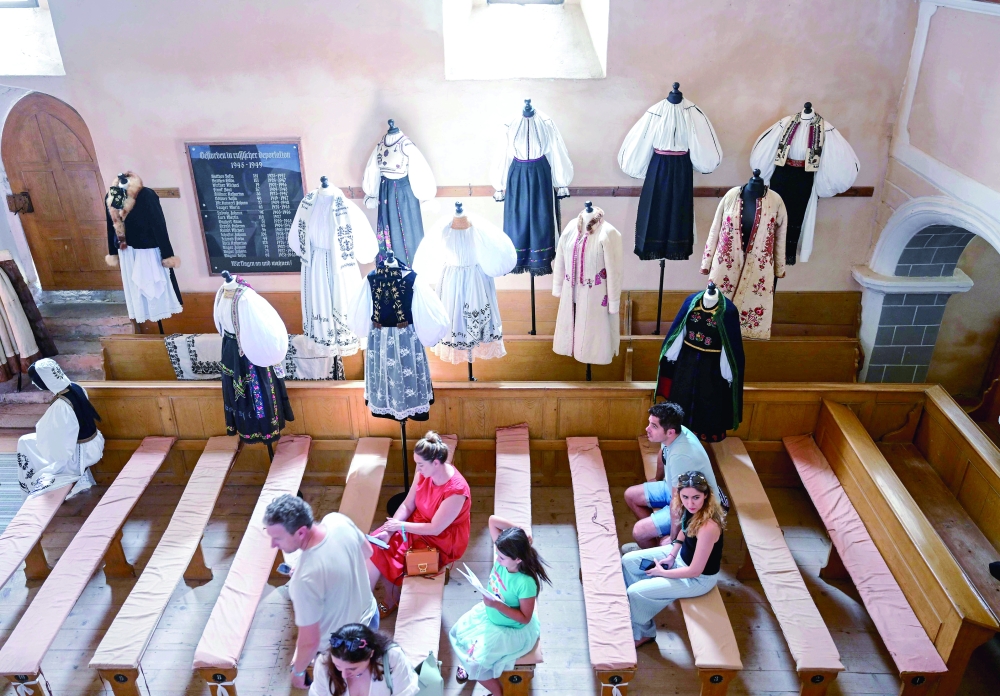 Visitors watch an exhibition of traditional Saxon outfits inside the fortified church in the village of Cincsor, Romania. — AFP
