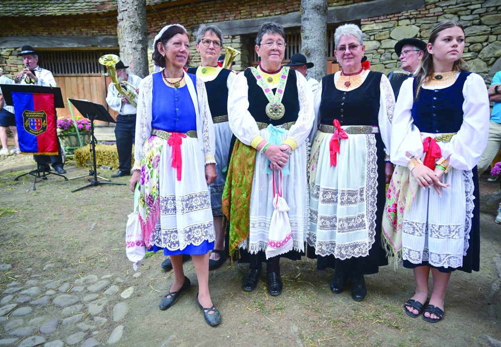 Visitors wearing traditional Saxon outfits pose for a photo at the fortified church in Crit during the "Haferland week" festival in the village of Crit, Romania. — AFP