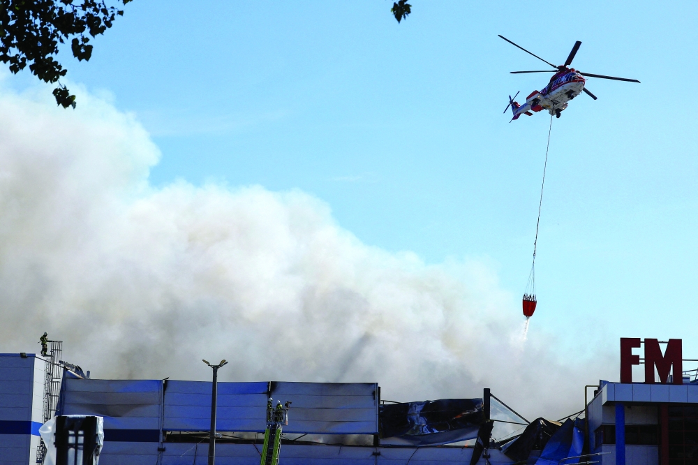 A firefighting helicopter drops water over a warehouse hit by a Russian drone strike, amid Russia's attack on Ukraine, in the Kyiv region. — Reuters