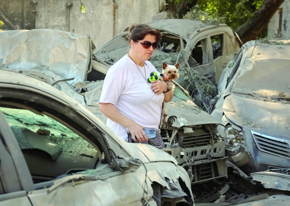 A woman with a dog walks among destroyed cars at a site of a Russian missile strike, in Kyiv, Ukraine.
- Reuters
