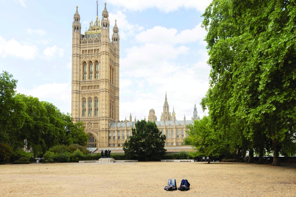 People people lay on the scorched grass in Victoria Tower Gardens, near the Houses of Parliament, in central London. - AFP