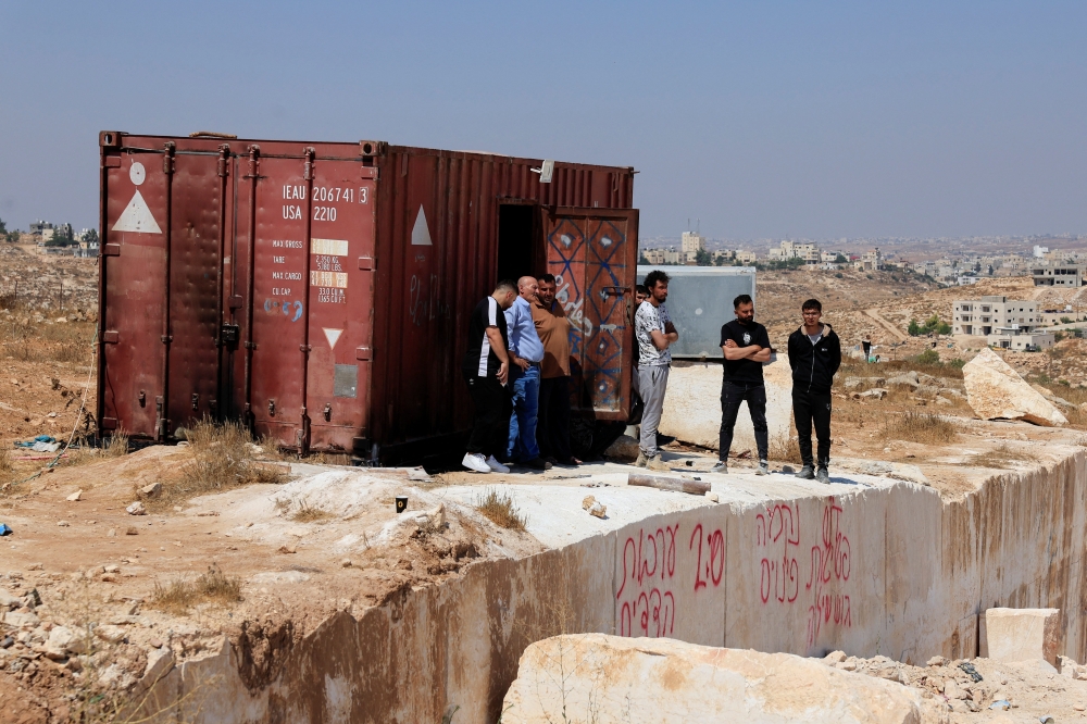 Palestinians inspect the damage after militant Israeli settlers set fire to stone quarry machinery in the West Bank. — Reuters