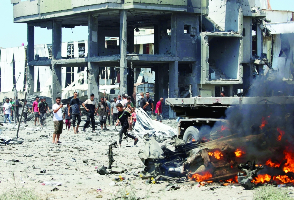 Palestinians gather at the site following an Israeli strike, carried out after the military warned Palestinian residents to evacuate the area of Maghazi, in the central Gaza Strip, on Sunday. — AFP