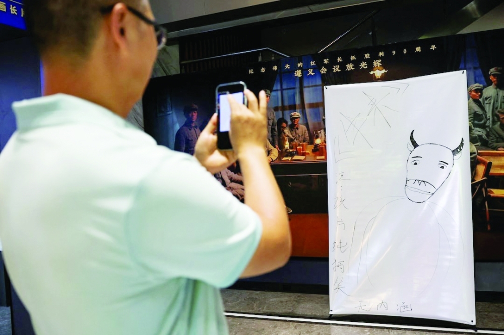 A man uses his phone to photograph a hand-drawn poster for the Chinese animated film Niu Lai at a cinema in Beijing— Reuters