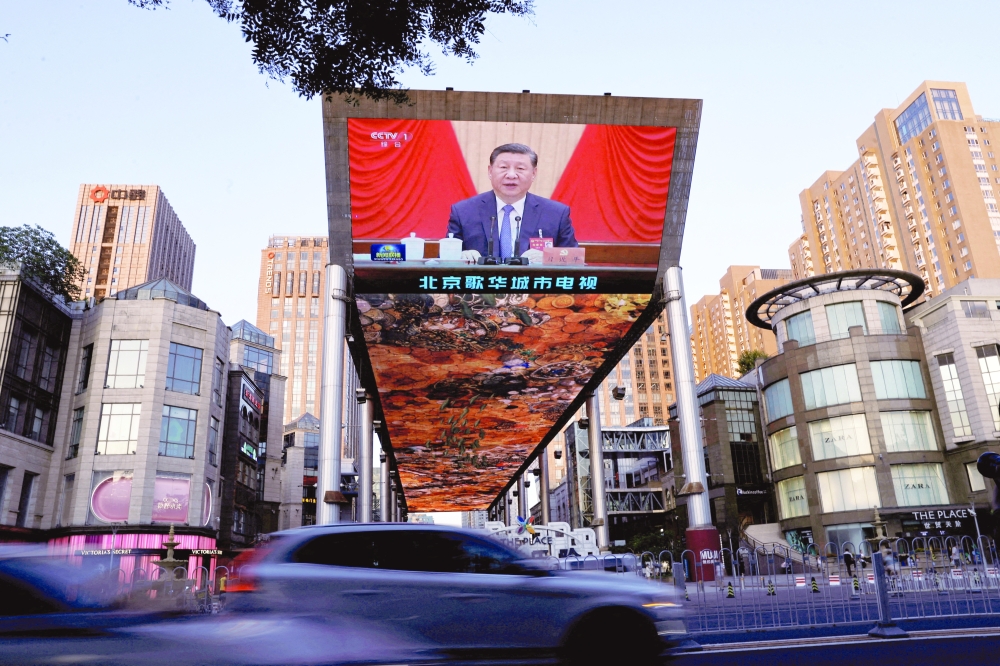 A giant screen shows news footage of Chinese President Xi Jinping in Beijing. — AFP file photo