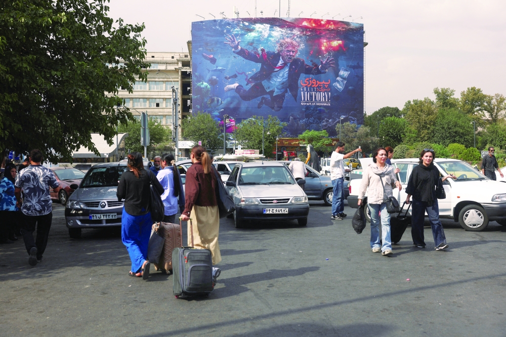 People walk near a billboard depicting US President Donald Trump on a building in Tehran. — Reuters