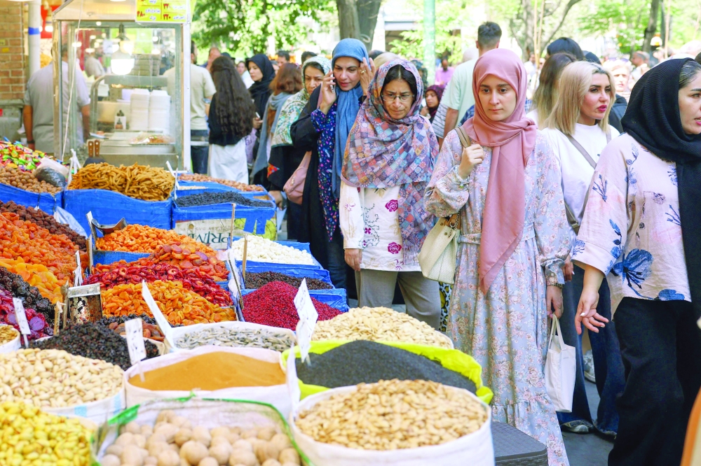 People walk past shops at a market area in Tehran on Monday. Iran responded with defiance to a US threat of the 'single greatest financial offensive ever', saying it was an admission of military defeat. - AFP