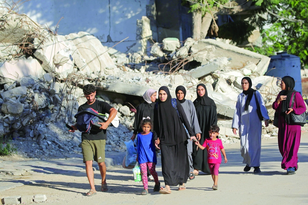 Palestinians leave their homes for cover following Israeli strikes at the Al Bureij refugee camp in central Gaza. — AFP