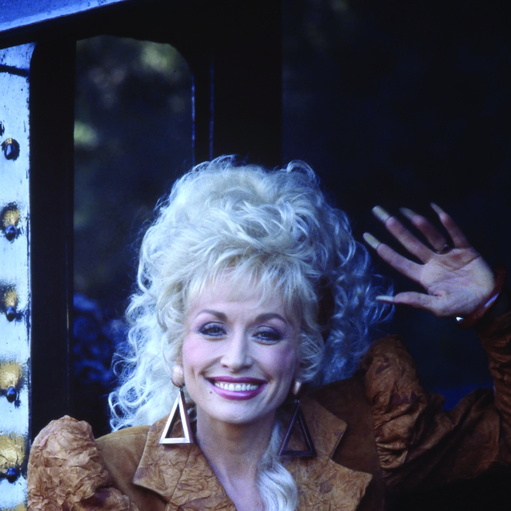 Dolly Parton, known for her distinctive style and larger-than-life personality, poses during the height of her career.