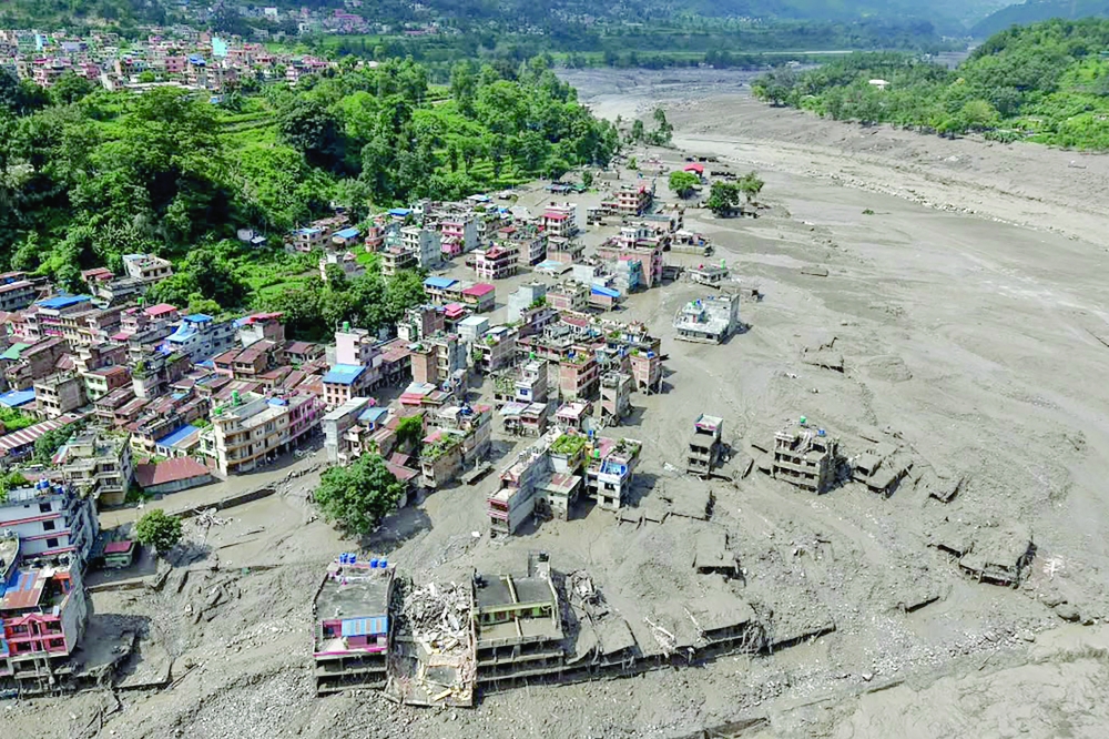 Houses lie partially submerged in muddy water along a riverside after flash floods at Trishuli Bazar in Nepal's Nuwakot district. — AFP