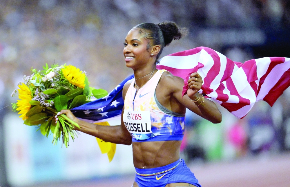 Masai Russell of the U.S. celebrates with a flag and flowers after winning the women's 100m hurdles final and setting a new world record REUTERS