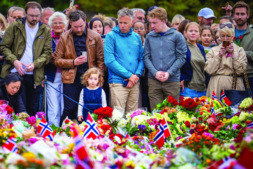 Mourners gather at a makeshift memorial of flowers to pay tribute to King Harald V of Norway who passed away, at the Royal Palace square in Oslo. - AFP