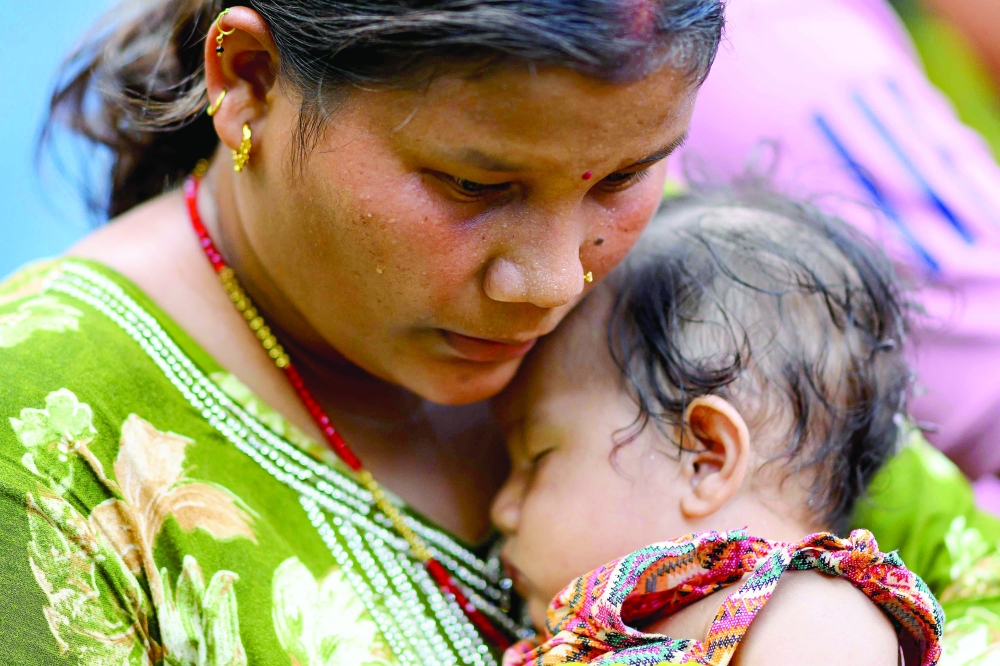A woman holds her five-month-old daughter after being rescued following the flash floods, at a military camp in Trishuli area of Nepal’s Nuwakot District. - AFP