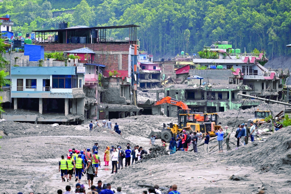 Workers use excavators to clear the mud at the Dhunge Bazaar in Nepal's Nuwakot district after flash floods and landslides hit the Nepal-Tibet border. — AFP