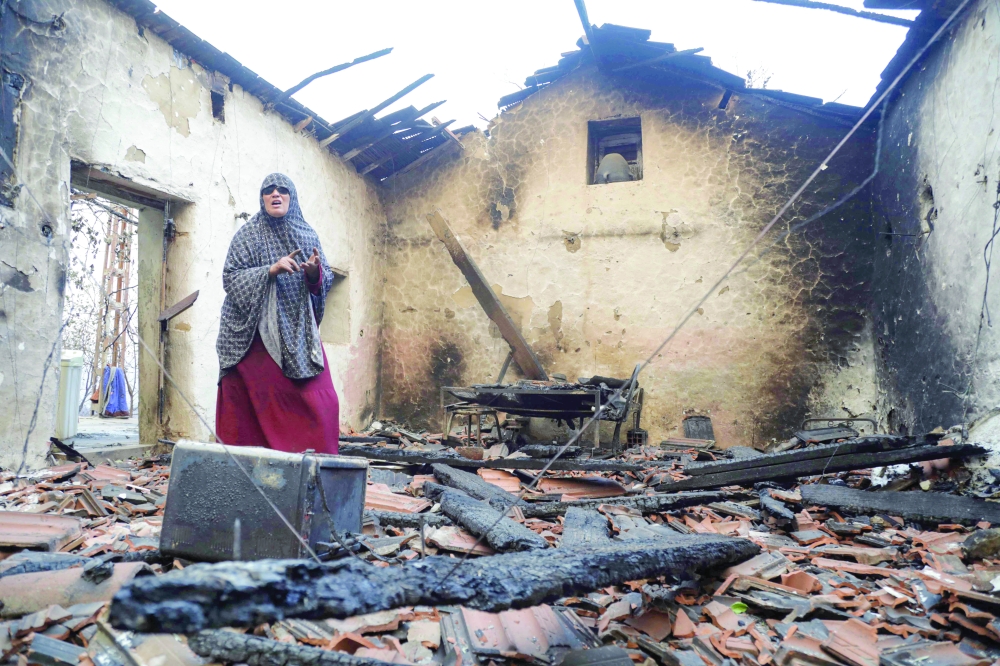 A woman inspects her damaged house after it was burned down in a forest fire in Bordj T'har, a town and commune in Algeria's northeastern Jijel Province, on August 27, 2026. 