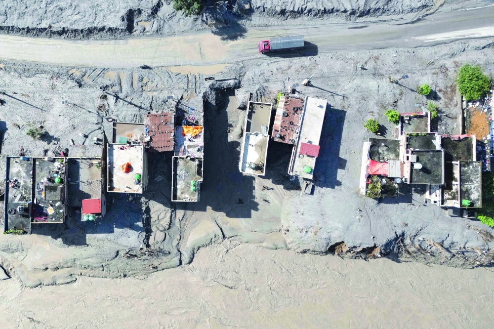 An aerial view shows a vehicle driving past houses covered in mud in the aftermath of flash floods at Baireni in Nepal's Dhading district. — AFP