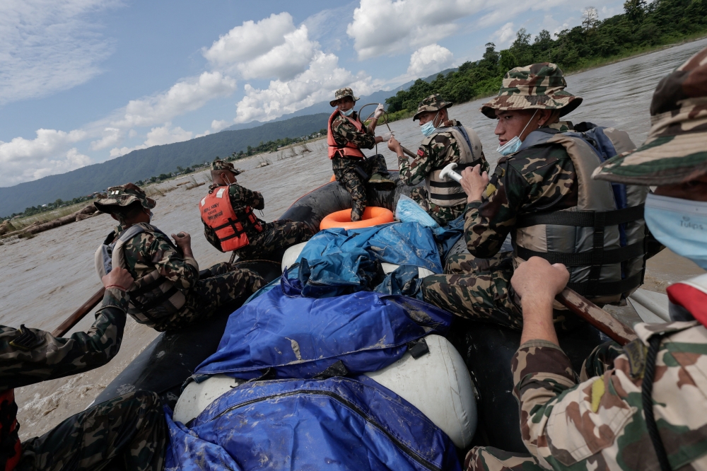 Members of the Nepal Army sit beside bodies they retrieved, which were washed away by flash floods and a mudslide in the Narayani River, Chitwan, Nepal, August 31, 2026.
