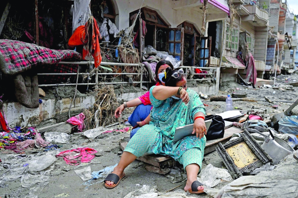 People salvage belongings from their homes following flash floods in Nepal's Nuwakot district. — AFP