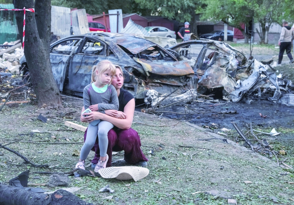 A mother and her daughter sit at a site of an apartment building damaged by a missile strike, in the town of Borispil, Ukraine. — AFP 