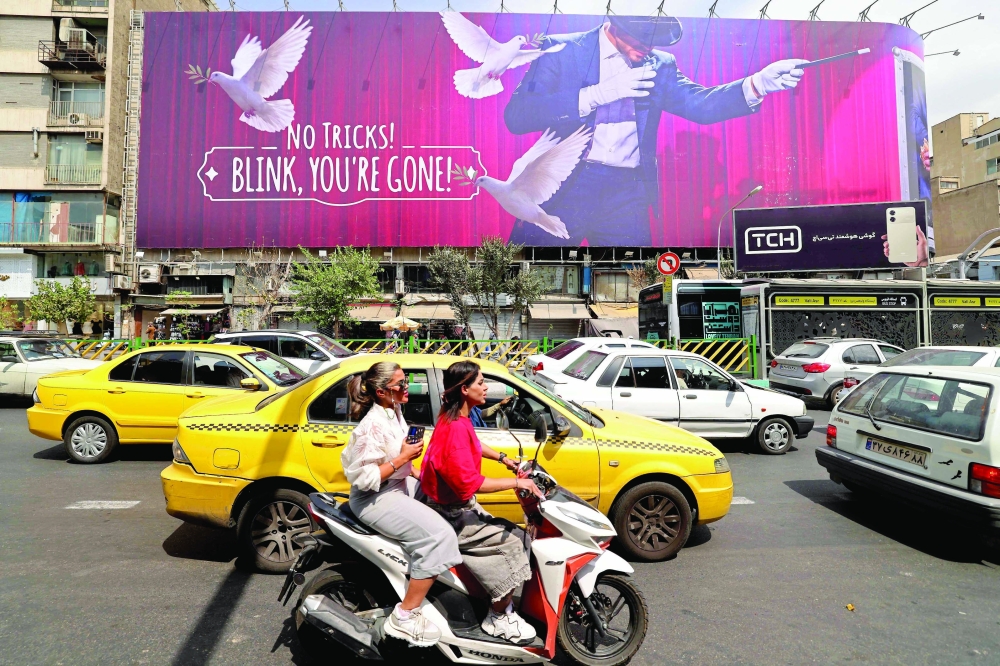 Commuters make their way past a billboard installed on a building along a busy street in downtown of Tehran. — AFP