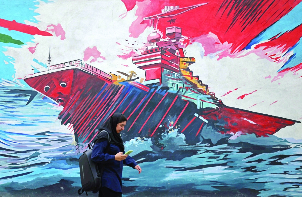 A commuter walks past a wall mural along the street in Tehran on Tuesday. - AFP