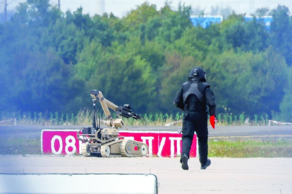 A police officer in protective clothing walks next to an explosive-disarming robot (EOD) at Leipzig/Halle Airport in Schkeuditz, Germany. — Reuters file photo