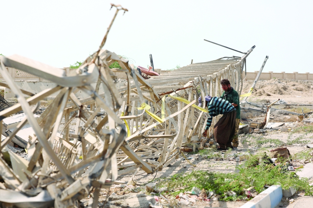 People inspect collapsed telecommunications infrastructure in the aftermath of an attack in Kuhestak, Sirik, Iran, on Saturday. — Reuters