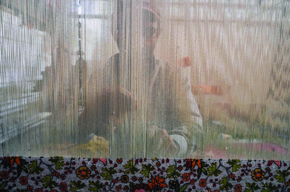A Kashmiri craftsman weaves a silk carpet at a factory in Srinagar. — AFP