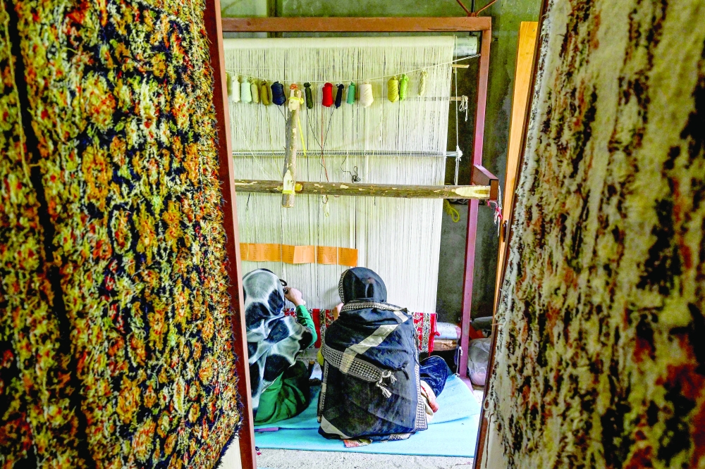 Kashmiri craftswomen weave silk carpets at a factory in Srinagar. — AFP