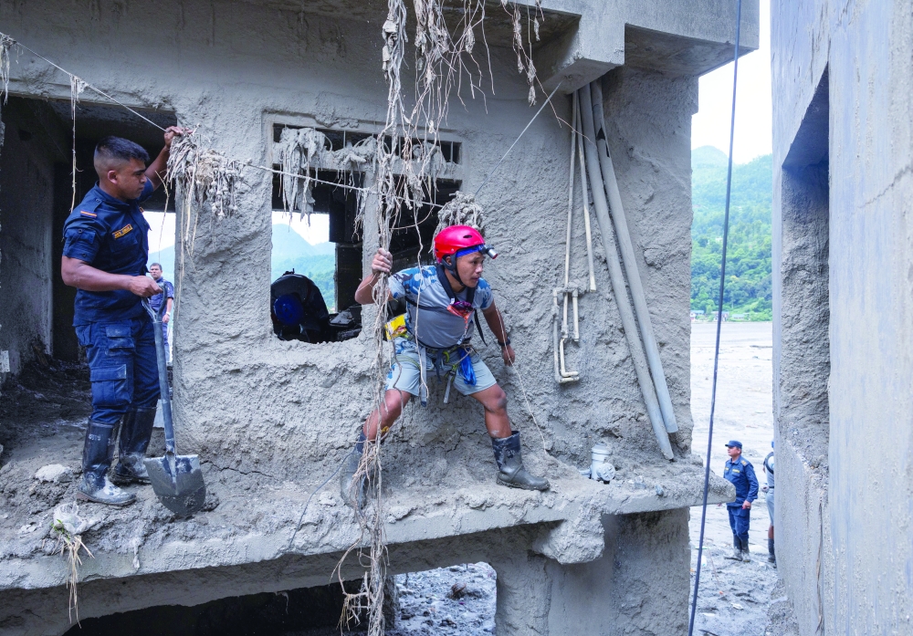 Nepal Police and Armed Police Force (APF) members search a house for survivors and victims in Betrawati. — Reuters 