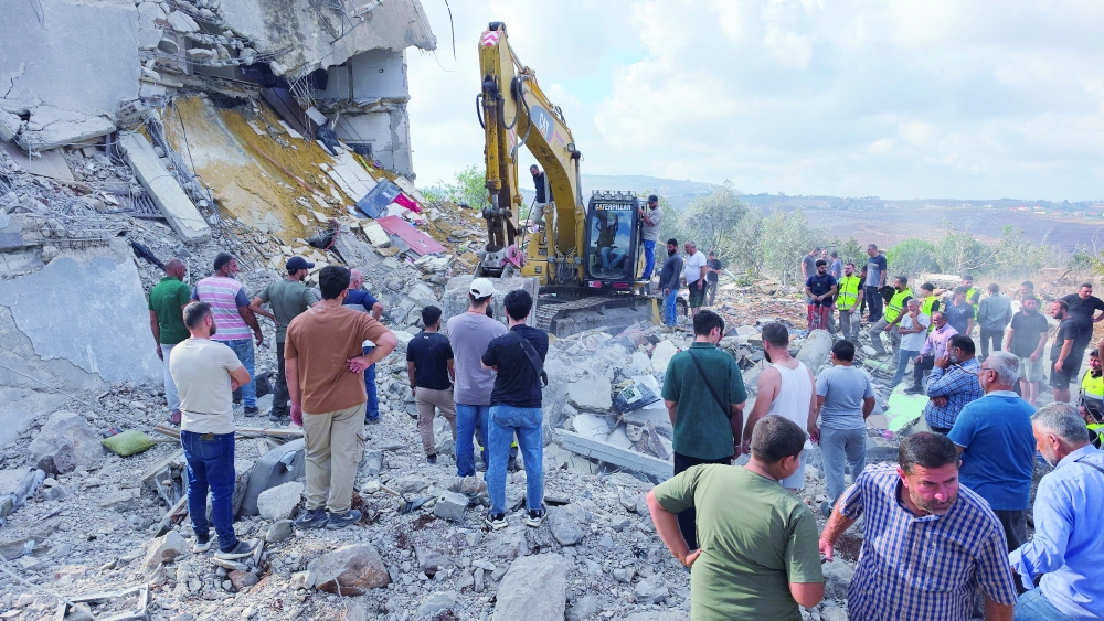 People stand amid rubble as heavy machinery operates at the site of an Israeli strike, in Arab Salim, Lebanon. — Reuters 