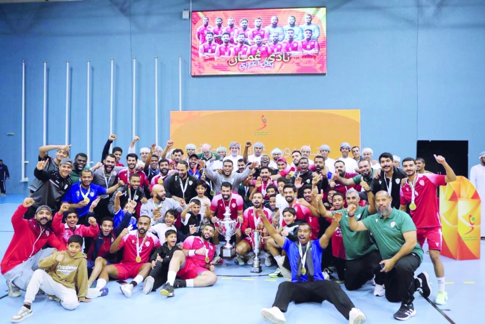 A group photo of the Oman Club handball team celebrating their victory in a championship.