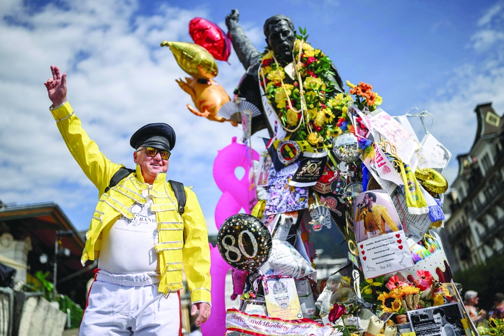 A fan poses next to the iconic Freddie Mercury statue overlooking Lake Geneva. — AFP